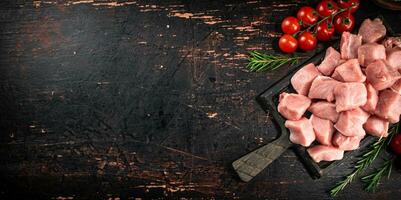 Stücke von roh Schweinefleisch auf ein Schneiden Tafel mit Tomaten. foto