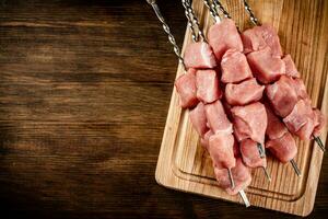 Schweinefleisch Kebab roh auf Spieße auf ein Schneiden Tafel. foto