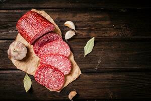 Stücke von Salami Würstchen mit Knoblauch und Bucht Blatt auf Papier. foto