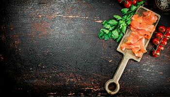 Scheiben von gesalzen Lachs mit Grüns und Tomaten auf ein Schneiden Tafel. foto