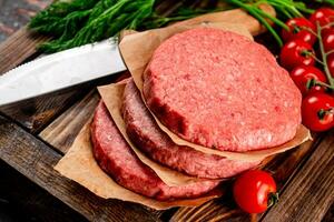 roh Burger auf ein hölzern Tablett mit Tomaten und Dill. foto