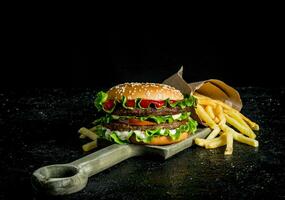 Burger mit Fritten auf das Schneiden Tafel. foto