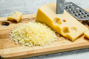 frisch gerieben Käse auf ein Hacken Tafel. foto