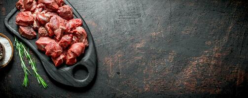 Schnitt roh Rindfleisch auf ein Schneiden Tafel mit Rosmarin. foto