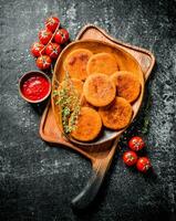 Fisch Schnitzel auf ein Teller mit Thymian, Tomaten und Soße. foto