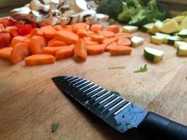 Messer gehackte Karotten und Pilze auf Küchentisch