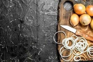 ganze und Ringe von frisch Zwiebeln auf ein Schneiden Tafel mit ein Messer. foto