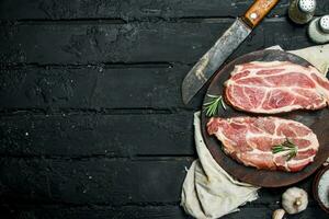 roh Schweinefleisch Steak mit ein alt Messer auf ein Schneiden Tafel. foto