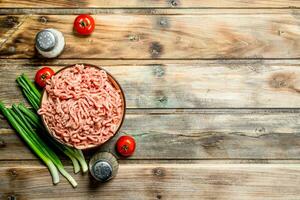 roh gehackt Rindfleisch im ein Schüssel mit Tomaten und Grün Zwiebeln. foto