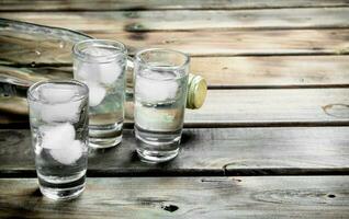 Wodka im ein Flasche und Brille mit Eis. foto