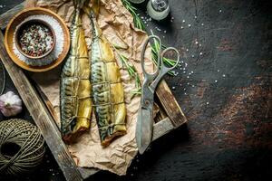 geräuchert Fisch Makrele auf ein Tablett mit Schnur, Schere und Gewürze. foto