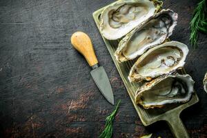 Meeresfrüchte. roh geöffnet Austern auf ein Schneiden Tafel mit Messer. foto