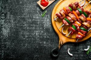 roh Rindfleisch Kebab mit Gemüse auf ein Schneiden Tafel mit Saucen, Rosmarin und Zwiebel Scheiben. foto