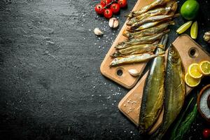 Typen von geräuchert Fisch mit Scheiben von Kalk, Zitrone, Tomaten und Kräuter. foto