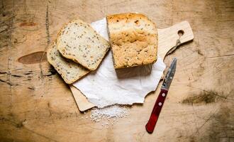 Brot mit Kräuter und Messer auf Tafel. foto
