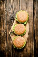 drei fertig Burger mit Fleisch und Gemüse auf hölzern Stand. foto