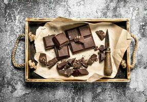 Stücke von dunkel Schokolade auf ein hölzern Tablett. foto