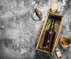 Flasche von Cognac im ein alt Box mit ein Zigarre. foto