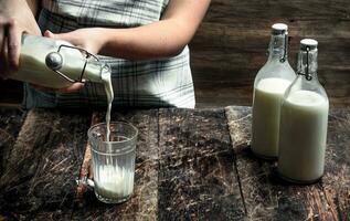 Frau gießt frisch Kuh Milch in ein Glas. foto