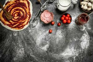 rollen oben Teig mit Tomate Soße und verschiedene Zutaten. foto