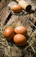 Eier im das Heu mit ein Stößel . auf hölzern Tisch. foto