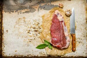 frisch roh Fleisch mit ein groß Messer und ein Bucht Blatt. foto