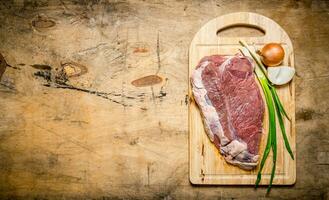 frisch roh Fleisch mit Zwiebeln auf ein hölzern Tafel. foto