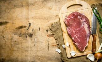 ein Stück von roh Fleisch mit ein Metzger Messer und ein Zwiebel. foto