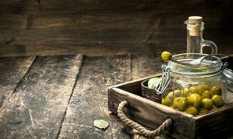 eingelegt Oliven mit Öl und Gewürze auf ein alt Tablett. foto