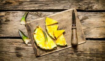 geschnitten frisch Ananas mit ein Messer auf ein Hacken Tafel. foto