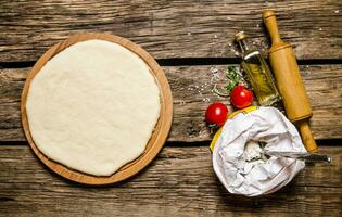 Pizza Teig mit Mehl, rollen Stift, Tomate und Olive Öl. foto