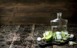 Wodka Schüsse mit Limette und Eis auf das Tafel. foto