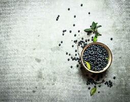 Blaubeeren mit Blätter im ein Tasse. auf Stein Tisch. foto