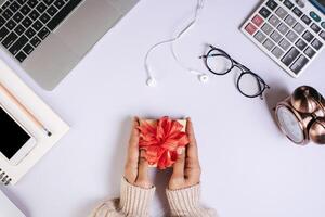 Draufsichthand, die geschenkbox auf arbeitsplatz hält. foto