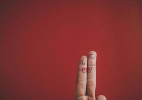 Finger mit Emotion auf rotem Hintergrund.