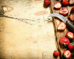 geschnitten Erdbeeren mit das alt Messer auf das Tafel. foto