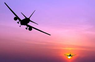 Silhouette eines kommerziellen Flugzeugs, das bei Sonnenuntergang fliegt foto