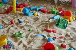 Sand und bunt Spielzeuge im ein Spielplatz drinnen. foto