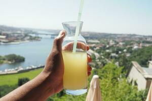 halten ein Glas von Orange Saft gegen Blau Himmel foto