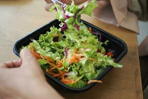 Frauen Essen Salat im ein Plastik Schüssel draussen foto