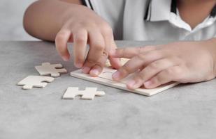 asiatischer kleiner Junge, der hölzernes Puzzlespiel spielt foto