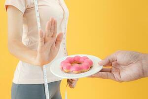 Ernährung und Diät. schönheit schlank weiblicher körper verwirren donut. frau in trainingskleidung erreicht gewichtsverlustziel für ein gesundes leben, verrückt nach dünnheit, dünner taille, ernährungsberaterin. foto