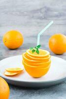frisch Orange Scheiben im ein Stapel, Minze Blätter und ein Stroh zum ein trinken. simuliert Orange Saft. Vertikale Aussicht foto