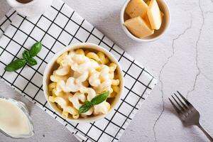 appetitlich Pasta mit Käse Soße und Basilikum im ein Schüssel auf das Tabelle oben Aussicht foto