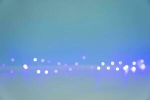 verschwommen Licht Glühbirnen von ein Licht Girlande glühend auf ein Blau Weiss Hintergrund foto