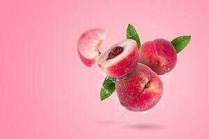 kreativ Layout gemacht von ganze und Scheibe von reif saftig Pfirsiche Obst und Wasser planschen auf ein Rosa Hintergrund foto