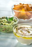Schalen von Hummus und Guacamole mit Tortilla Chips foto