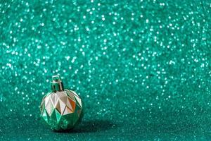 silberne Weihnachtskugel auf glänzendem grünem Hintergrund. Neujahrskonzept