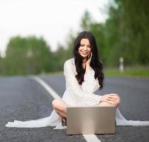 junge Frau mit Laptop auf Landstraße foto