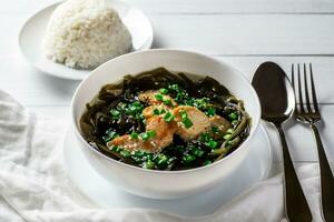 Koreanisch Seetang Suppe mit Fleisch im Weiß Schüssel und gekocht Reis. Geburtstag Suppe. traditionell Koreanisch Küche. gesund Diät. Schwangerschaft. Brauch. foto